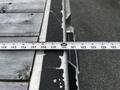 A tape measure lays across a surface with markings showing measurements in inches and feet