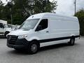 A 2019 Mercedes-Benz Sprinter van with a white exterior and black front grille parked at an angle showcasing its cargo area and wheels