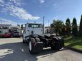 A 2003 Freightliner M2 106 truck is parked with its rear visible showing large tires and a black chassis with a white cabin