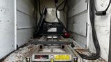 Inside the cargo area of a 2007 Ford F-550 a metal ramp is positioned on a textured floor with wires and equipment visible in the background