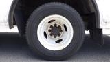 A close-up of a white wheel with a black tire mounted on a 2011 Ford Econoline