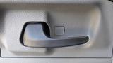 Close-up of a black door handle on a 2015 Ford Econoline interior with a textured surface and a rectangular button nearby