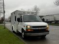 A white 2016 Chevrolet Express van with emergency lights on the roof parked on the street