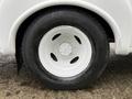 Close-up of a white wheel rim with a black tire on a 2015 Ford Econoline, featuring a five-bolt pattern and water droplets on the rubber surface