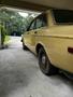 A vintage 1978 Volvo 244 in yellow parked with a slight angle showing the rear and side view of the car