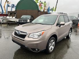 A 2016 Subaru Forester is parked in the foreground featuring a light brown exterior and a spacious design with a distinctive grille and headlights