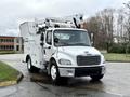A white 2005 Freightliner M2 106 truck with a bucket lift and utility body, positioned at a slight angle facing forward