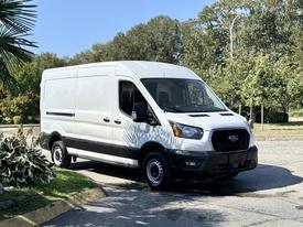 A 2022 Ford Transit van in white with black accents parked with its side door closed and front facing forward