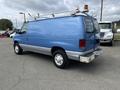 A blue 2009 Ford Econoline van with a ladder rack on the roof and rust on the rear bumper