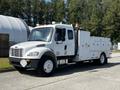 A white 2004 Freightliner M2 truck with a utility body featuring multiple compartments and tools mounted on the side