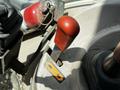 A close-up of the control lever of a 2011 Kubota M8540D tractor with an orange handle and nearby safety warning label
