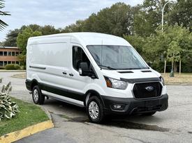 White 2022 Ford Transit van with sliding side door and black trim parked at an angle with the front slightly turned towards the viewer