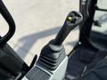 A close-up of the joystick control for a 2022 Caterpillar 306 excavator featuring buttons and a trigger on top