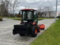 A 2018 Kubota B2650 compact tractor with large tires and a black front bucket attachment parked on a road