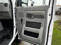 The interior door panel of a 2017 Ford Econoline featuring a gray color scheme with a handle and control switches