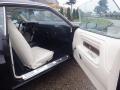 A 1974 Dodge Challenger with a black exterior and a white interior featuring bucket seats and a simple dashboard design