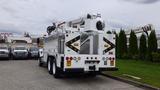 A 2012 International 7400 bucket truck featuring a raised aerial platform and utility storage compartments on the sides