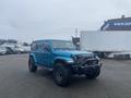 A blue 2020 Jeep Wrangler with a rugged front bumper and off-road tires parked in a lot