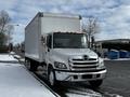 A white 2019 Hino 338 24 foot cube truck with a large cargo area and chrome accents parked on a snowy street