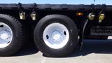 Close-up of a large white tire mounted on a black truck chassis with visible bolts and a clear tread pattern