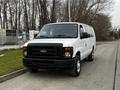 A white 2011 Ford Econoline van parked on a street with gray wheels and a black front grille