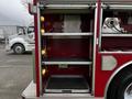 An open compartment of a red 1995 Freightliner FL70 showing metal shelves and lights on the sides