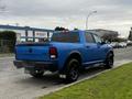 A blue 2021 RAM 1500 Classic pickup truck with black rims and a four-wheel drive badge parked on the street