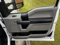 The interior door panel of a 2016 Ford F-150 featuring a gray design with a black armrest and window control buttons