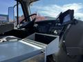 The interior of a 2012 Freightliner M2 112 truck showing the driver's seat dashboard and mounted monitor with a metal storage compartment in the foreground