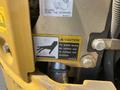 A caution label on a yellow John Deere machine warning to avoid burns and not to contact hot surfaces
