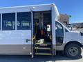 A white 2020 Chevrolet Express shuttle bus with open doors revealing steps and an accessible entrance