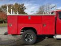 A red 2013 Chevrolet Silverado 3500HD with a utility bed featuring side storage compartments and chrome wheels