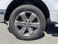 A close-up view of a silver alloy wheel from a 2014 Ford F-150 showing six lug nuts and a Michelin tire