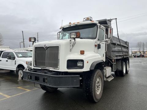A 2003 International 5600i dump truck with a white cab and a black dump bed parked at an outdoor location