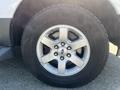 Close-up of a silver wheel featuring five spokes and a Ford emblem mounted on a black tire with visible tread pattern