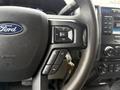 Close-up of the steering wheel of a 2018 Ford F-550 featuring audio control buttons and the Ford logo