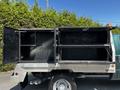 A 2008 Ford F-550 with an open service body displaying two compartments one on top of the other both empty and with black interiors