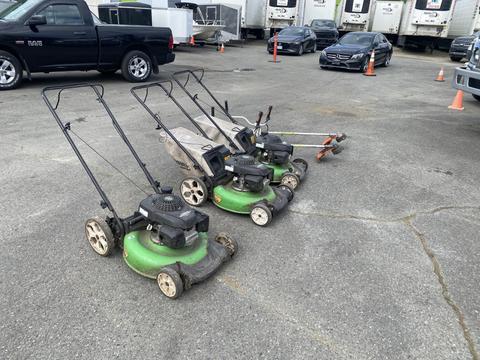Three Honda Lawnboy mowers with green bodies and black engines next to two Stihl line trimmers on a concrete surface