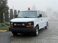 A 2016 GMC Savana van is parked with a visible amber light on the roof and a front grill featuring the GMC logo