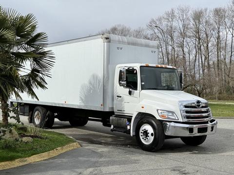 A 2017 Hino 338 truck with a white cargo box is parked at an angle on a driveway
