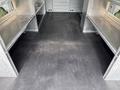Interior of a 2023 Ford Transit with metallic shelves on both sides and a smooth black floor