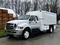 A white 2013 Ford F-650 truck with a boxy cargo area and large wheels parked on a wet surface