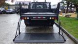 A black 2011 Ford F-550 with a flatbed and lowered ramp positioned for loading items