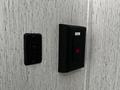 A black light switch and electrical outlet mounted on a textured gray wall