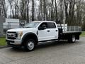 A 2017 Ford F-550 truck with a flatbed design is shown in a side view featuring a white exterior and chrome accents