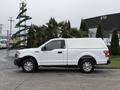 A white 2018 Ford F-150 pickup truck with a canopy parked on a street