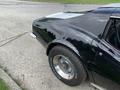 A black 1972 Chevrolet Corvette with a sleek design featuring a silver stripe and white wall tires showcasing its classic style and curves