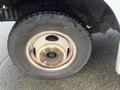 Close-up of a wheel and tire from a 2012 Ford Econoline showing worn rubber and rust on the wheel rim