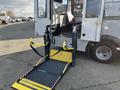 A 2018 Chevrolet Express with a wheelchair lift extended from the side featuring yellow safety bars and a textured platform