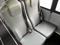 Two plush gray bus seats with seat belts attached, designed for passenger safety in a vehicle interior